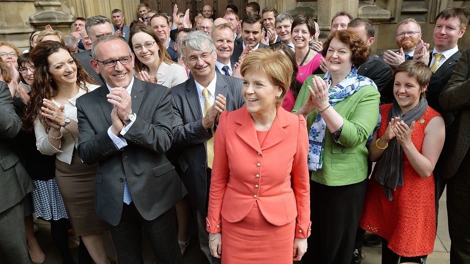 SNP leader Nicola Sturgeon stands with the party's 56 MPs as they gather outside Parliament for the first time since the election