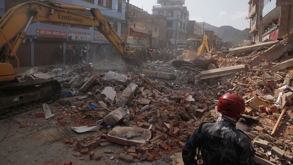 Earthmovers clear the debris after a building collapsed in Kathmandu, Nepal. (AP)