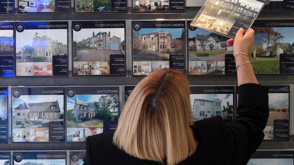 A woman looking at houses for sale at a Scottish estate agent
