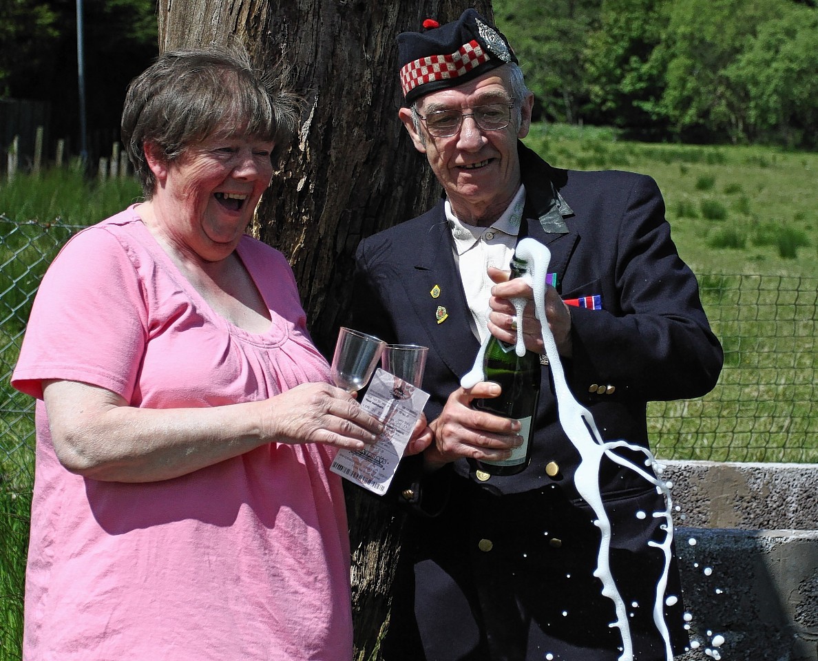 Betty and Geordie Rhodick crack open the champagne after winning on the lottery