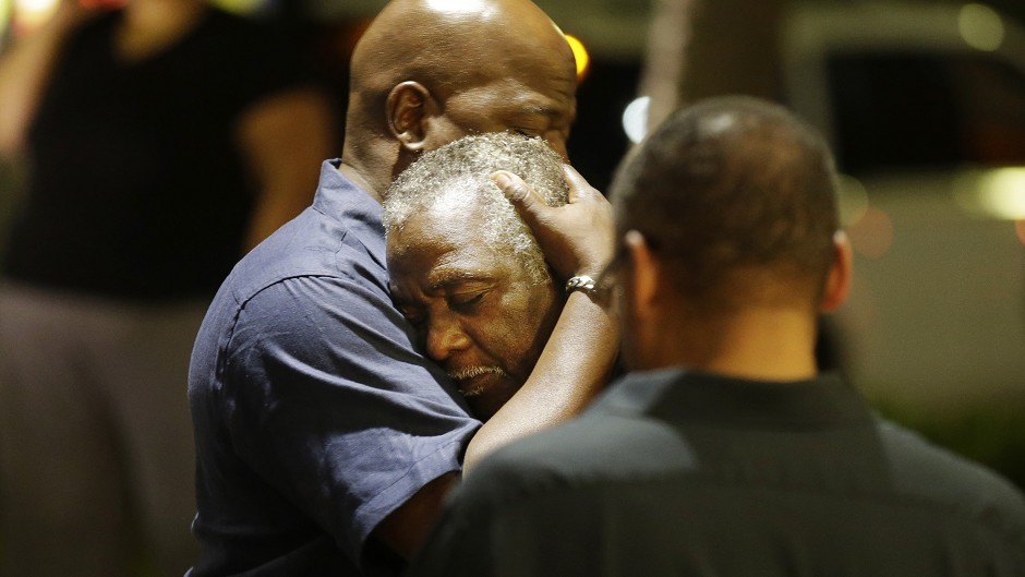 Worshippers embrace following a group prayer across the street from the scene of the shooting (AP)