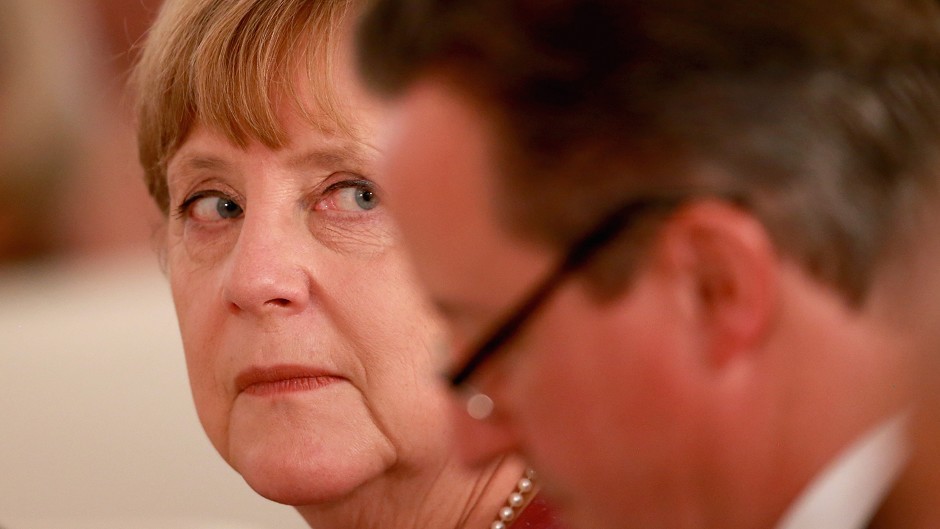 Angela Merkel looks at David Cameron during a state banquet attended by the Queen in Berlin