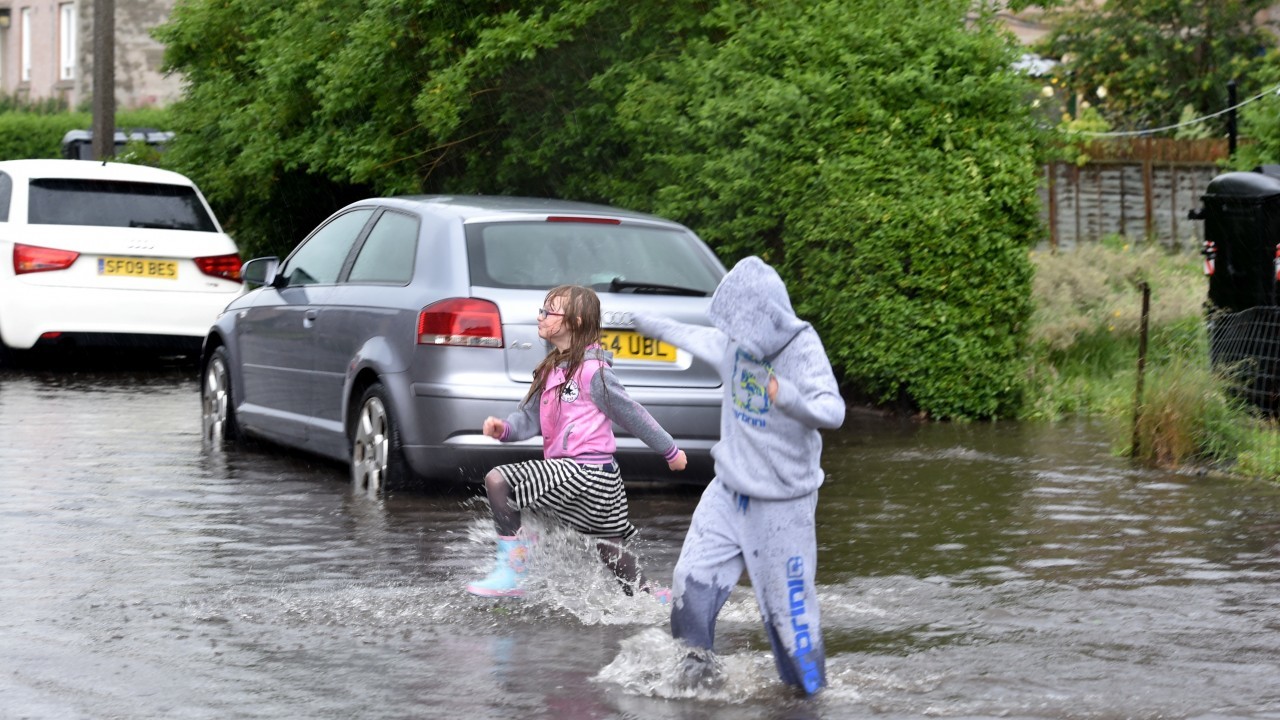 Amy Moir, 8 and Kai Neil 10 enjoy the floods at  Willowpark Crescent.
Picture by Colin Rennie