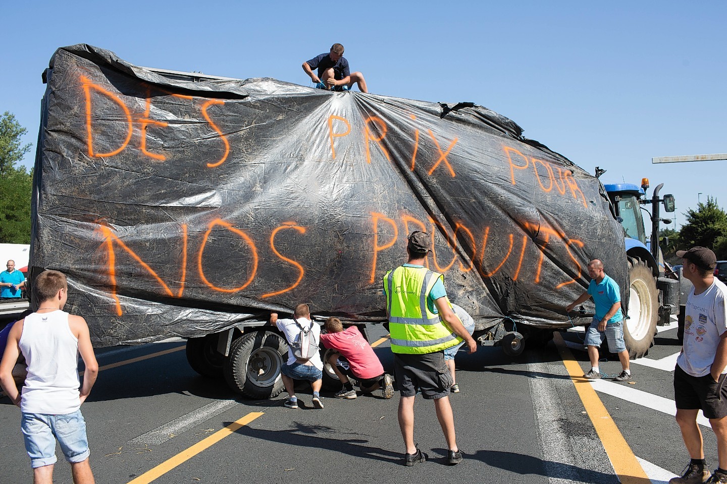 Farmers set up a large plastic sheet as they block the highway 