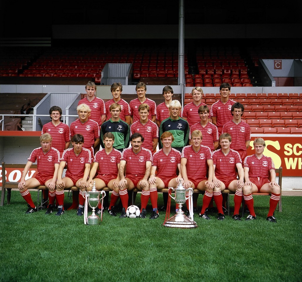 The Dons 1984/85 squad. Back row, left to right: Steve Cowan, Peter Weir, Doug Bell, Ian Angus, Frank McDougall and Willie Falconer. Middle Row, left to right: Tommy McQueen, Neale Cooper, Jim Leighton, Tommy McIntyre, Bryan Gunn, Brian Mitchell and Billy Stark. Front row, left to right: Ian Porteous, John Hewitt, Eric Black, Willie Miller, Alex McLeish, Neil Simpson, John McMaster and Stewart McKimmie. With the Premier League Championship trophy and the Scottish Cup.