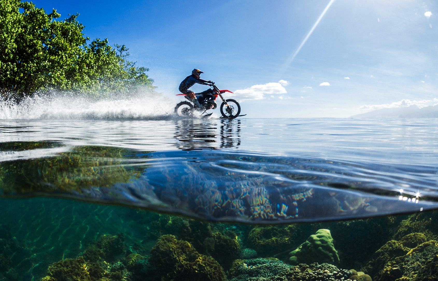 In this April, 2015, photo provided by DC Shoes, daredevil Robbie Maddison in his latest stunt rides his motorcycle across waves in Tahiti, French Polynesia, using ski-like devices on his wheels.  (Tim McKenna/DC Shoes via AP)