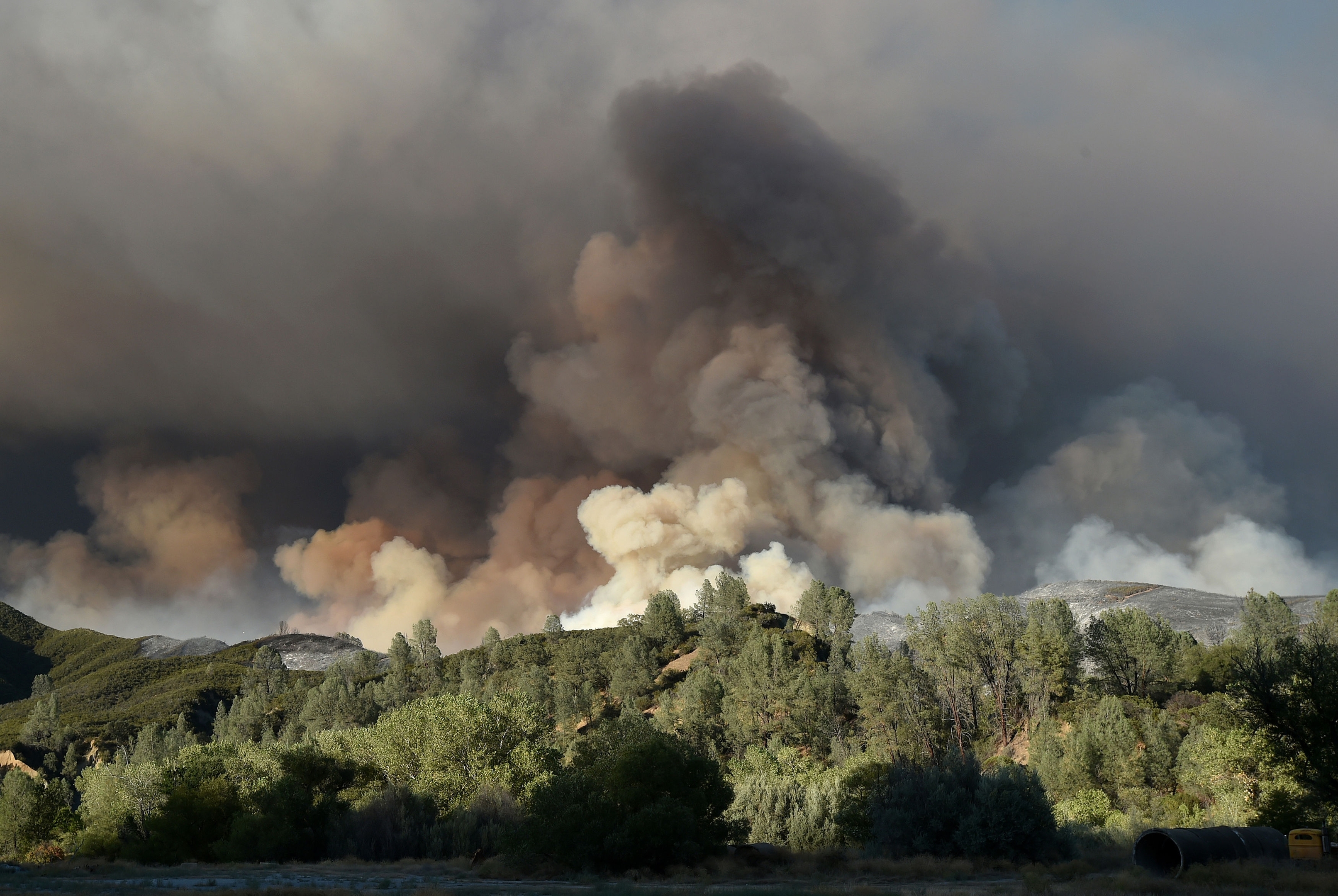 A plume of smoke rises above a hillside as the Rocky Fire burns near Clearlake, Calif., on Monday, Aug. 3, 2015. The fire has charred more than 60,000 acres and destroyed at least 24 residences. (AP Photo/Josh Edelson)