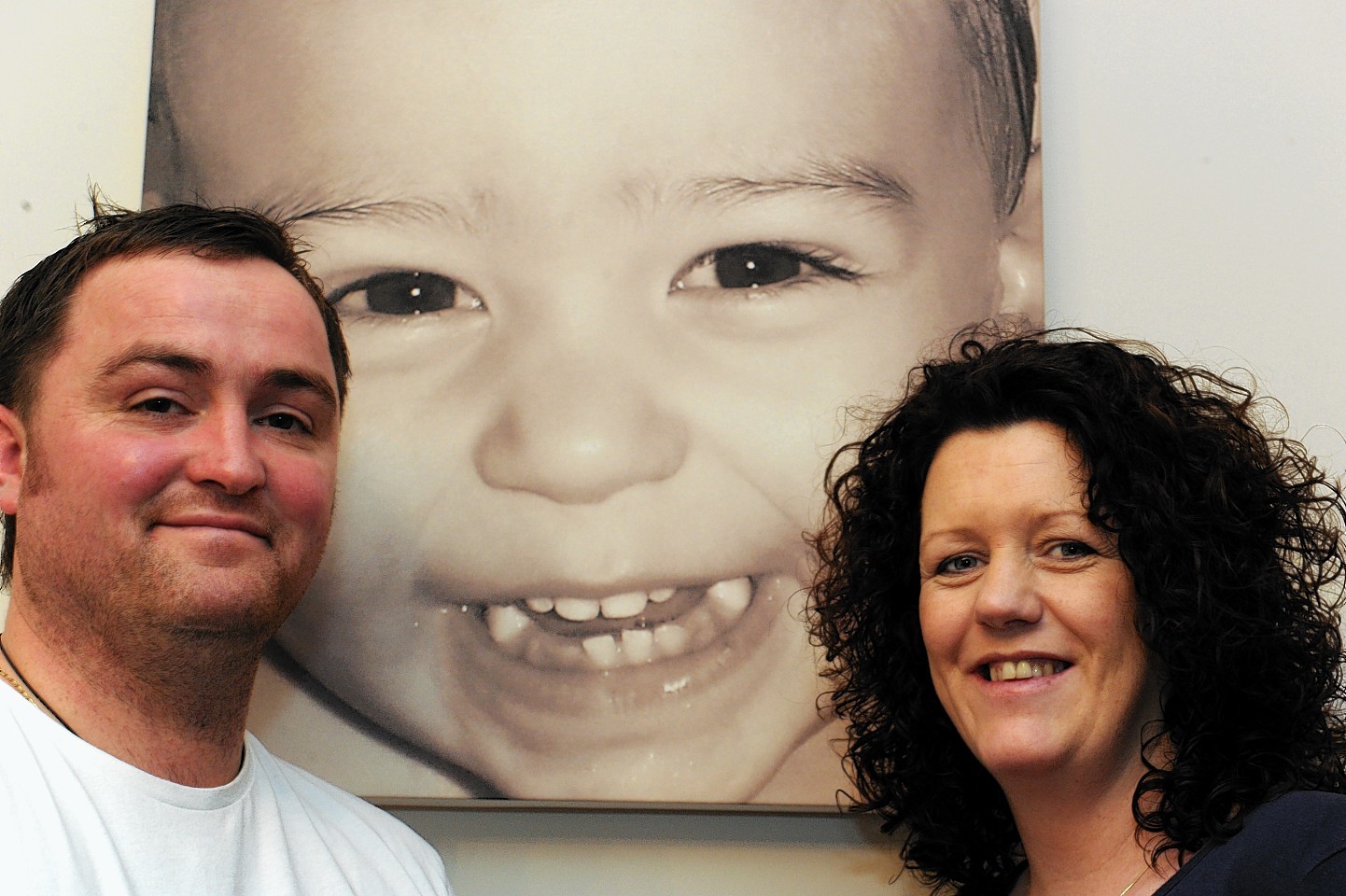Chris, left, and Angela Main, right, at their home in Dunbar Street, Lossiemouth with a photo of their deceased son, Logan Main.