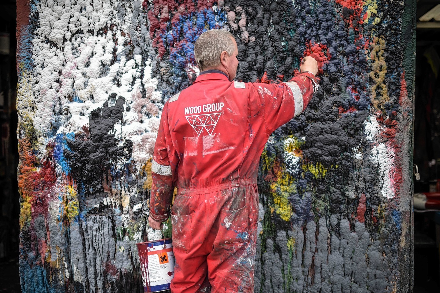 Painter Adrian Buchan cleans his brush on a wall at W Bruce Ship Painters in Fraserburgh,