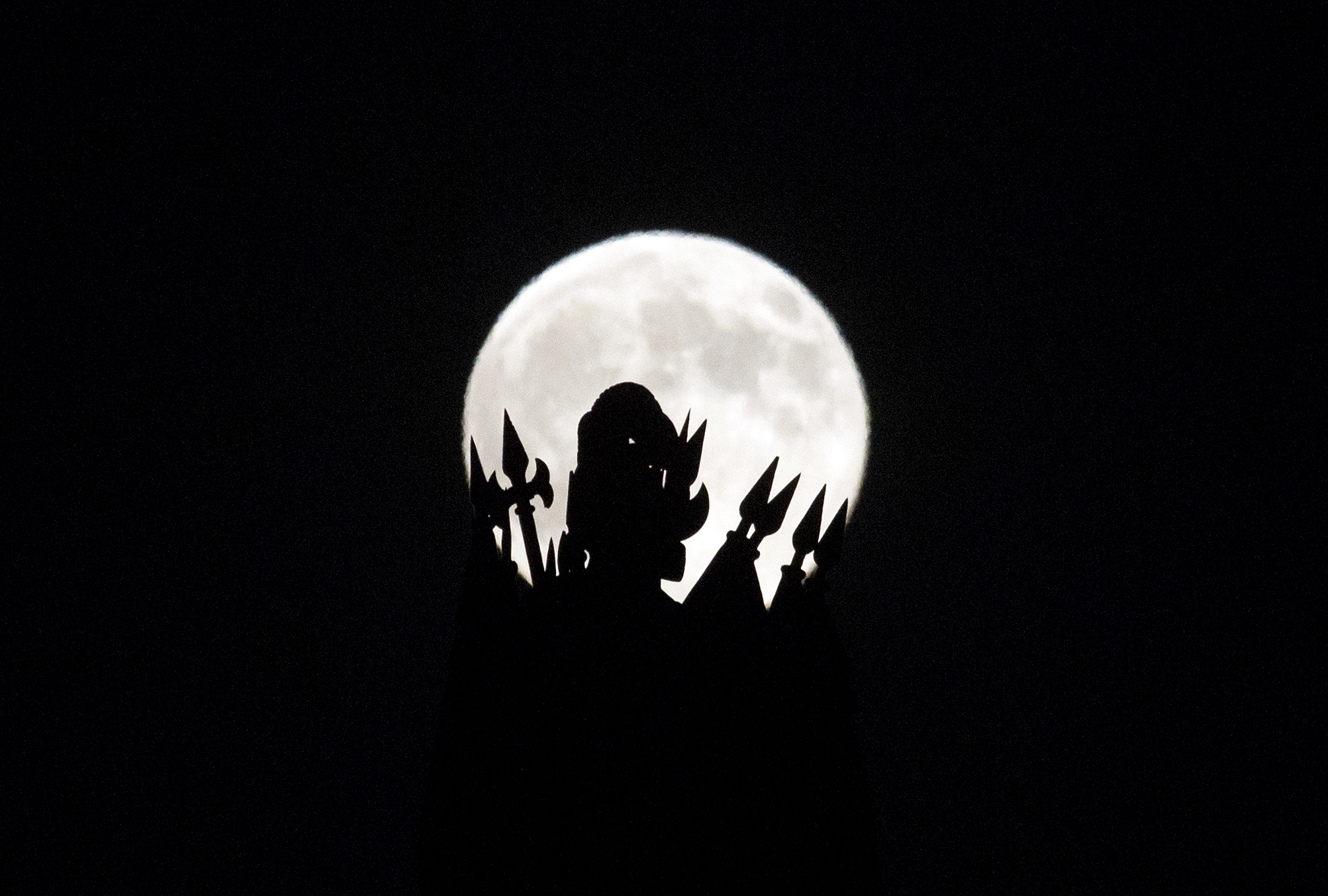 A statue on the roof of the Portuguese finance ministry in Lisbon is silhouetted against a so-called "supermoon"