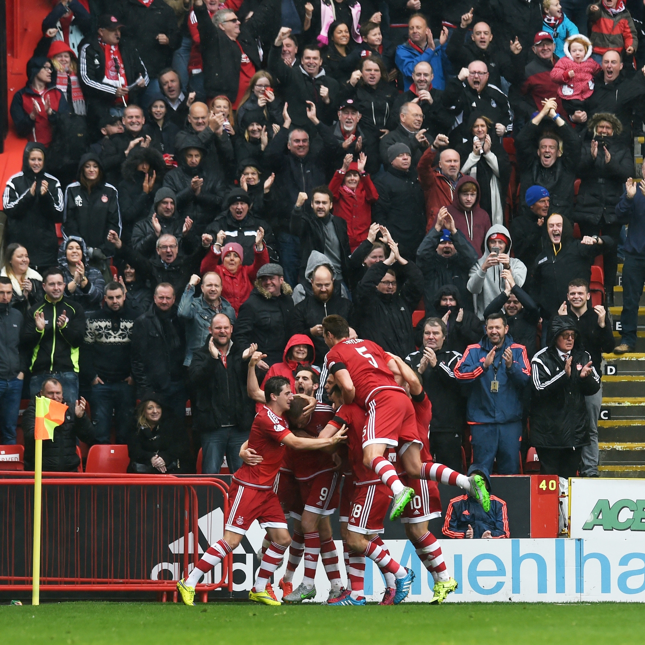 The Aberdeen players celebrate Rooney's equalising goal in front of the Dons fans