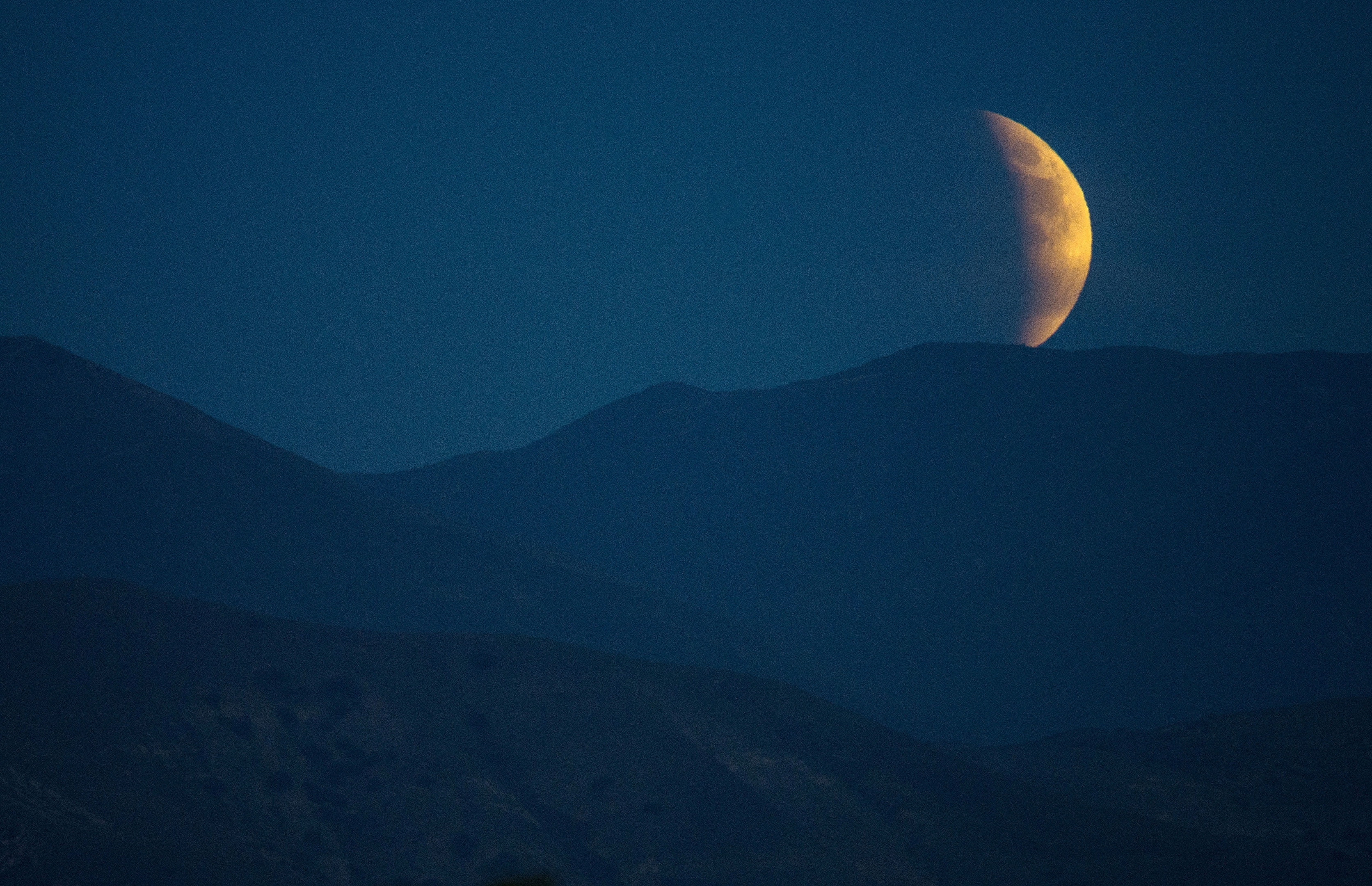 Earth's shadow begins to obscure the view of a so-called supermoon during a total lunar eclipse over the eastern hills of Orange County in California,