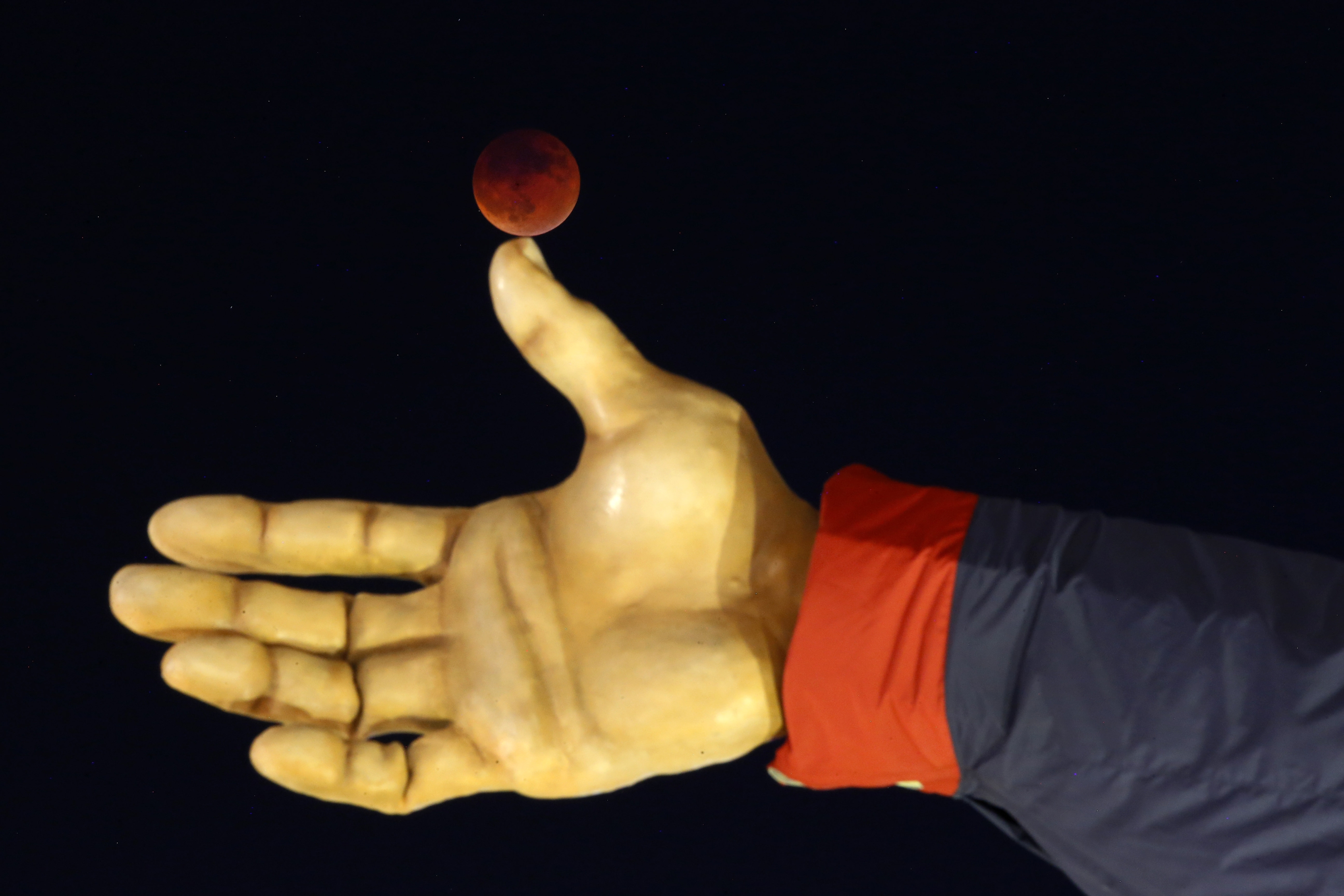 The so-called supermoon appears during a lunar eclipse behind Big Tex, Sunday