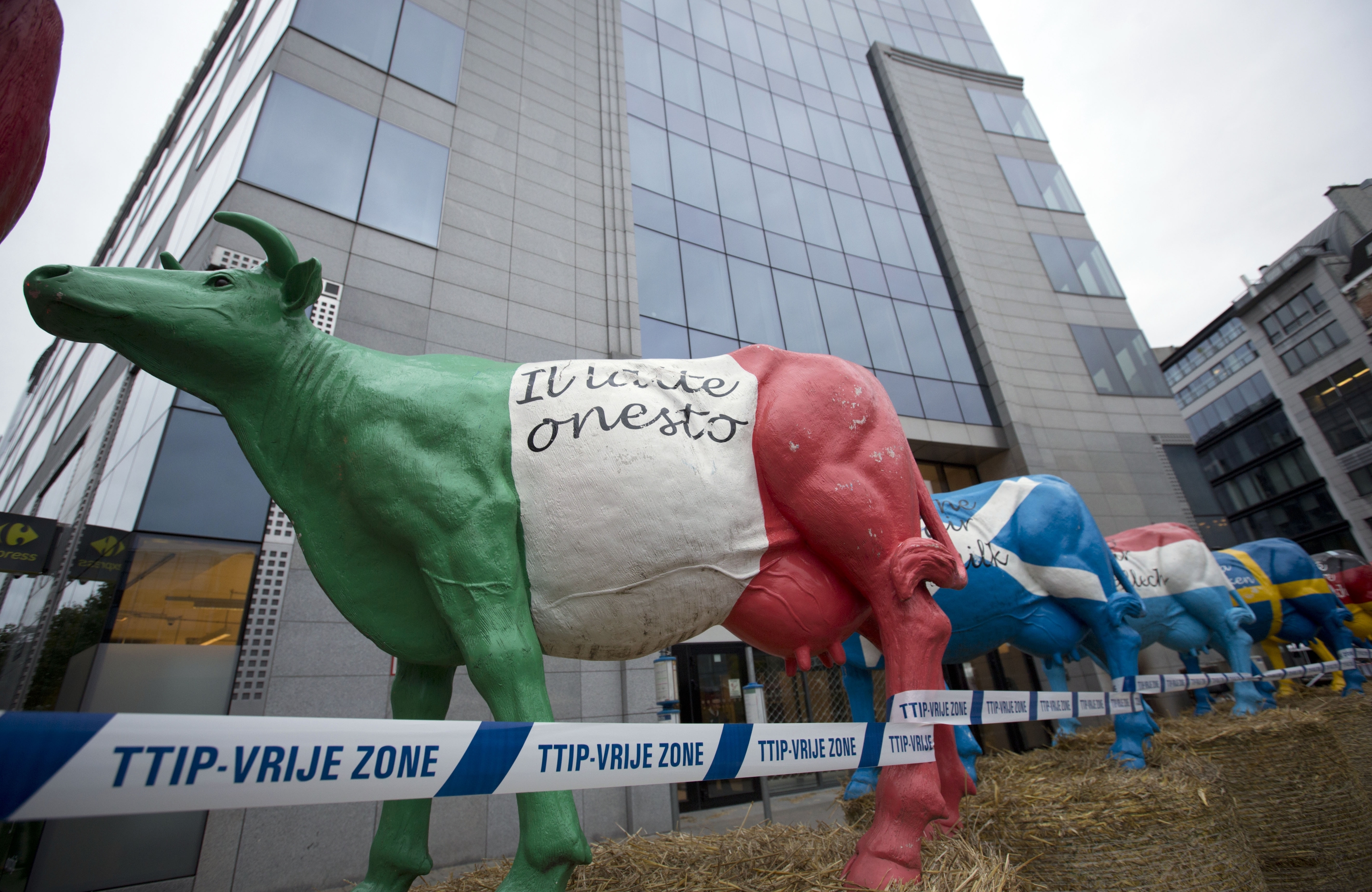 Plastic cows are lined up on hay bales in front of EU headquarters 