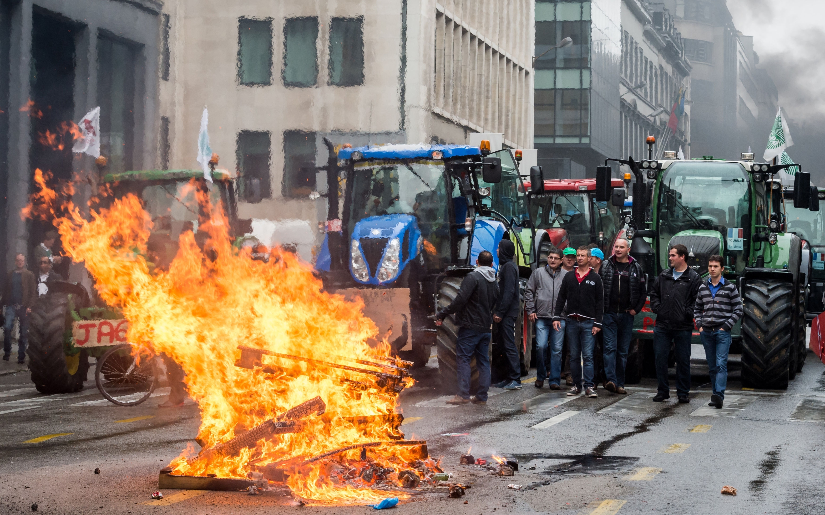 Farmers stand next to their tractors after lighting a fire 