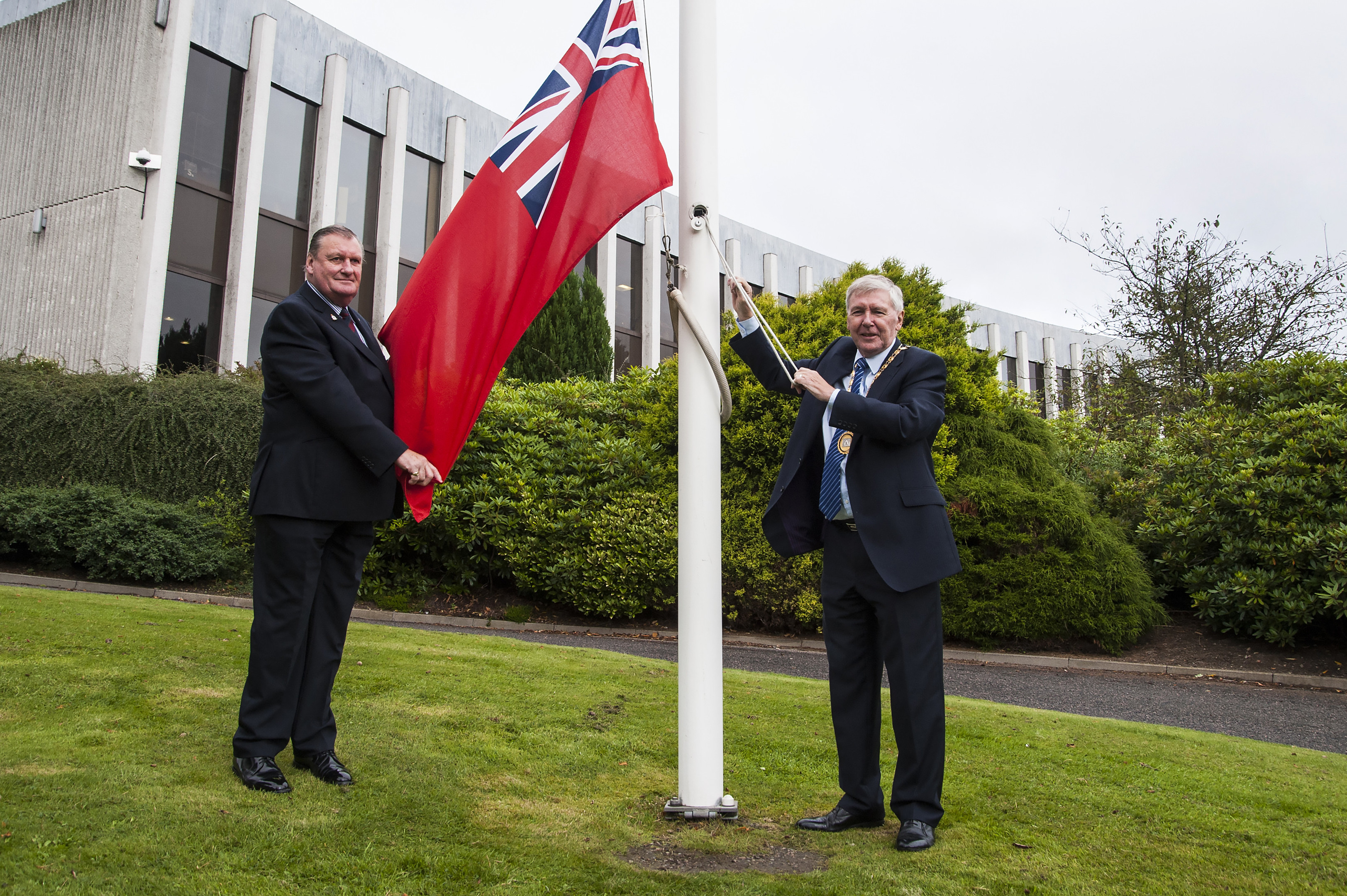 Councillors Allan Hendry and Hamish Vernal raise the red ensign of the Merchant Navy