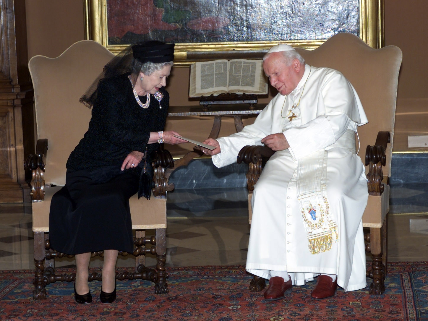 Queen Elizabeth II exchanges letters with with Pope John Paul II during an audience at the Vatican in Rome, Italy, Tuesday October 17, 2000. Dressed in black and wearing a veil, the Queen was greeted by the 80-year-old leader of the Roman Catholic Church at the door of his study. During a private meeting lasting 20 minutes, they are thought to have discussed progress towards Christian unity and the troubles in Northern Ireland. The Queen arrived in Rome Monday at the start of four day State visit to Italy. 