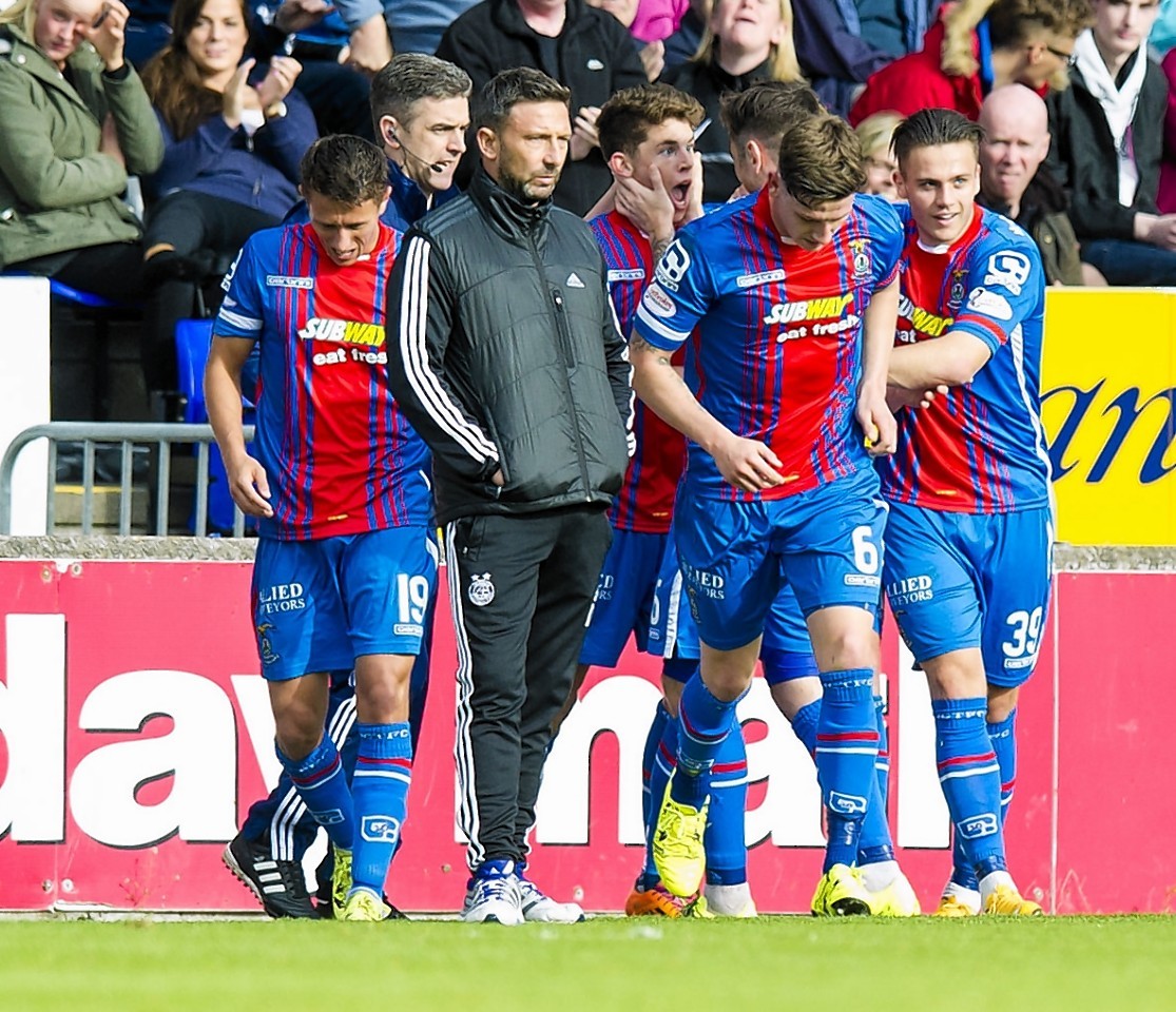 A dejected Derek McInnes is surrounded by celebrating Caley Thistle players  