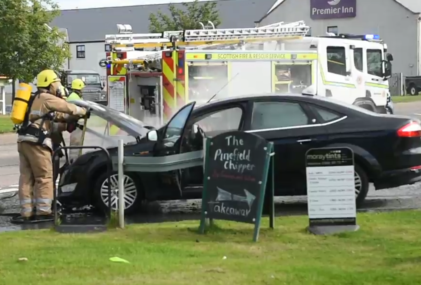 Firefighters battle the car fire in Elgin on the A96
