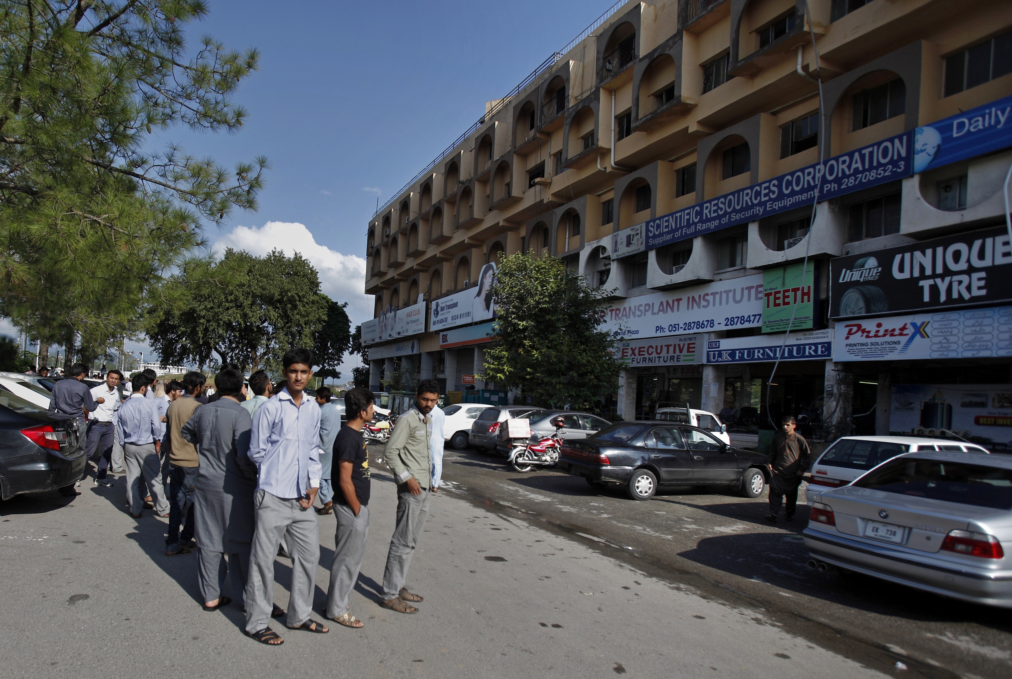 People stand outside their offices after a severe earthquake is felt in Islamabad, Pakistan
