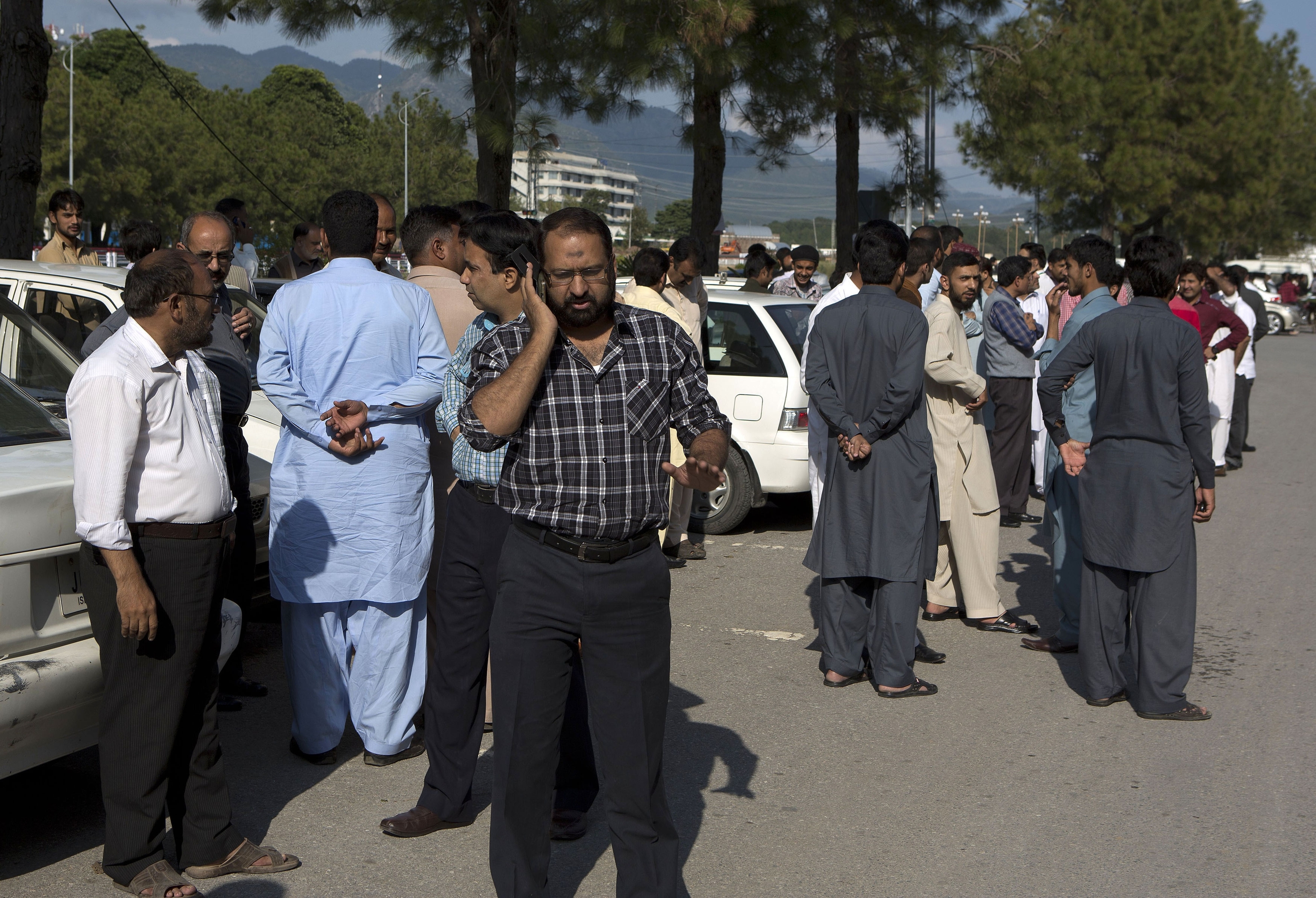 People stand outside their offices after a severe earthquake is felt in Islamabad, Pakistan, 