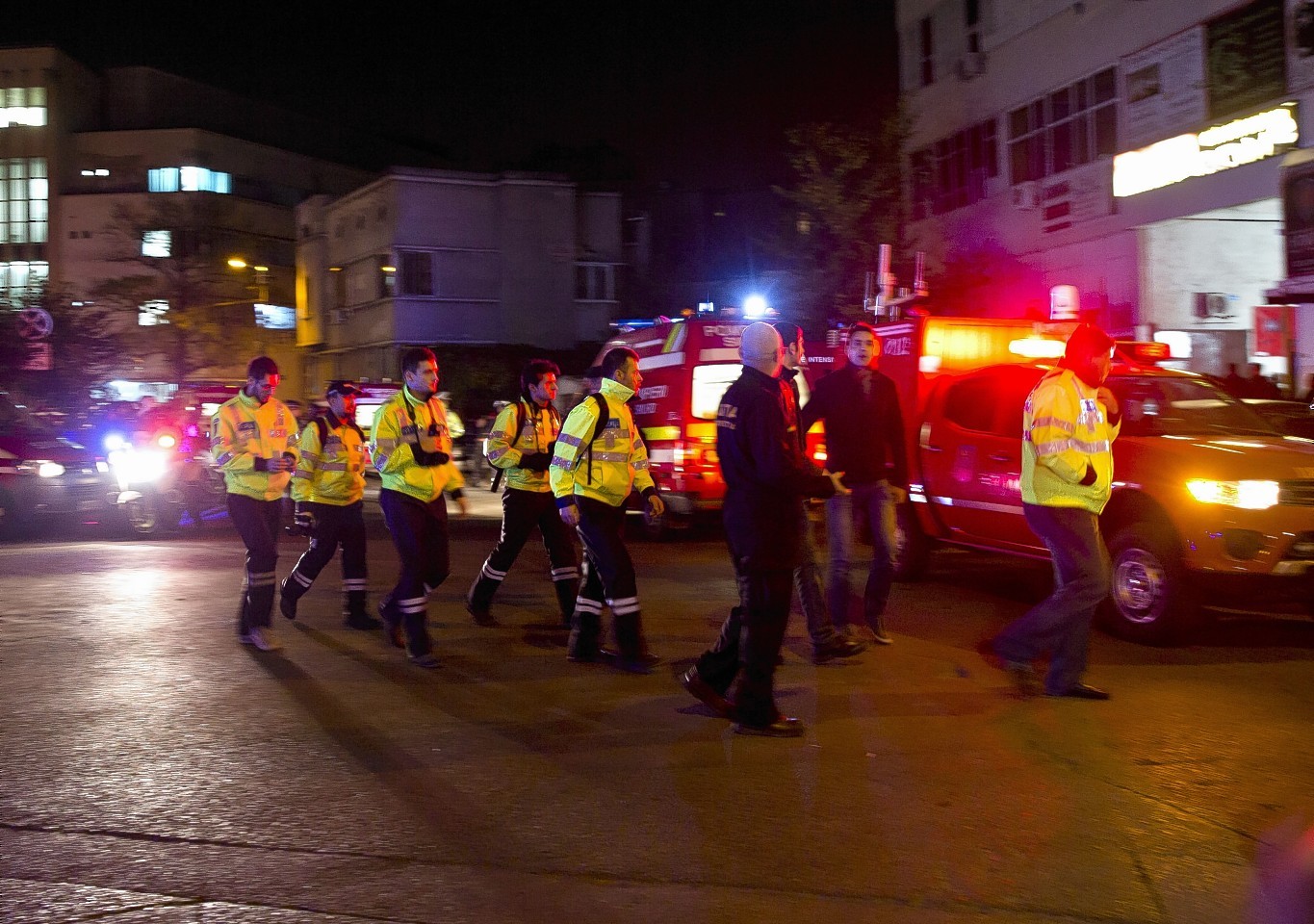 Emergency workers walk outside the scene of an explosion that occurred in a club in Bucharest