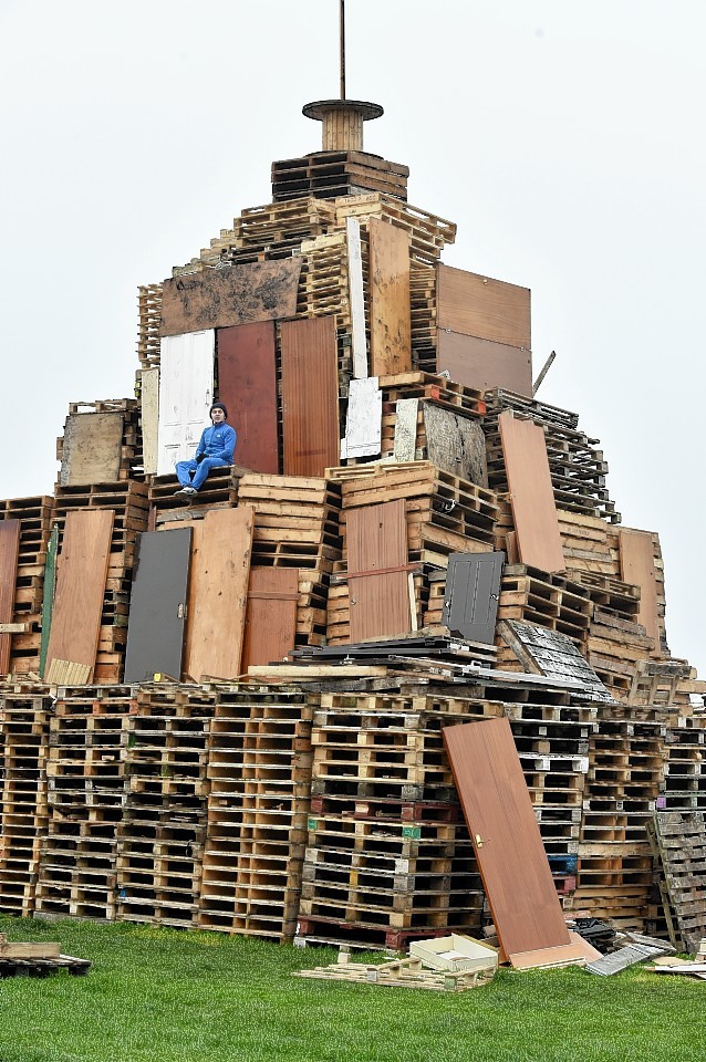 One of the organiser, Simon Gemmell, sits on the pallets as preparation of the huge bonfire continues