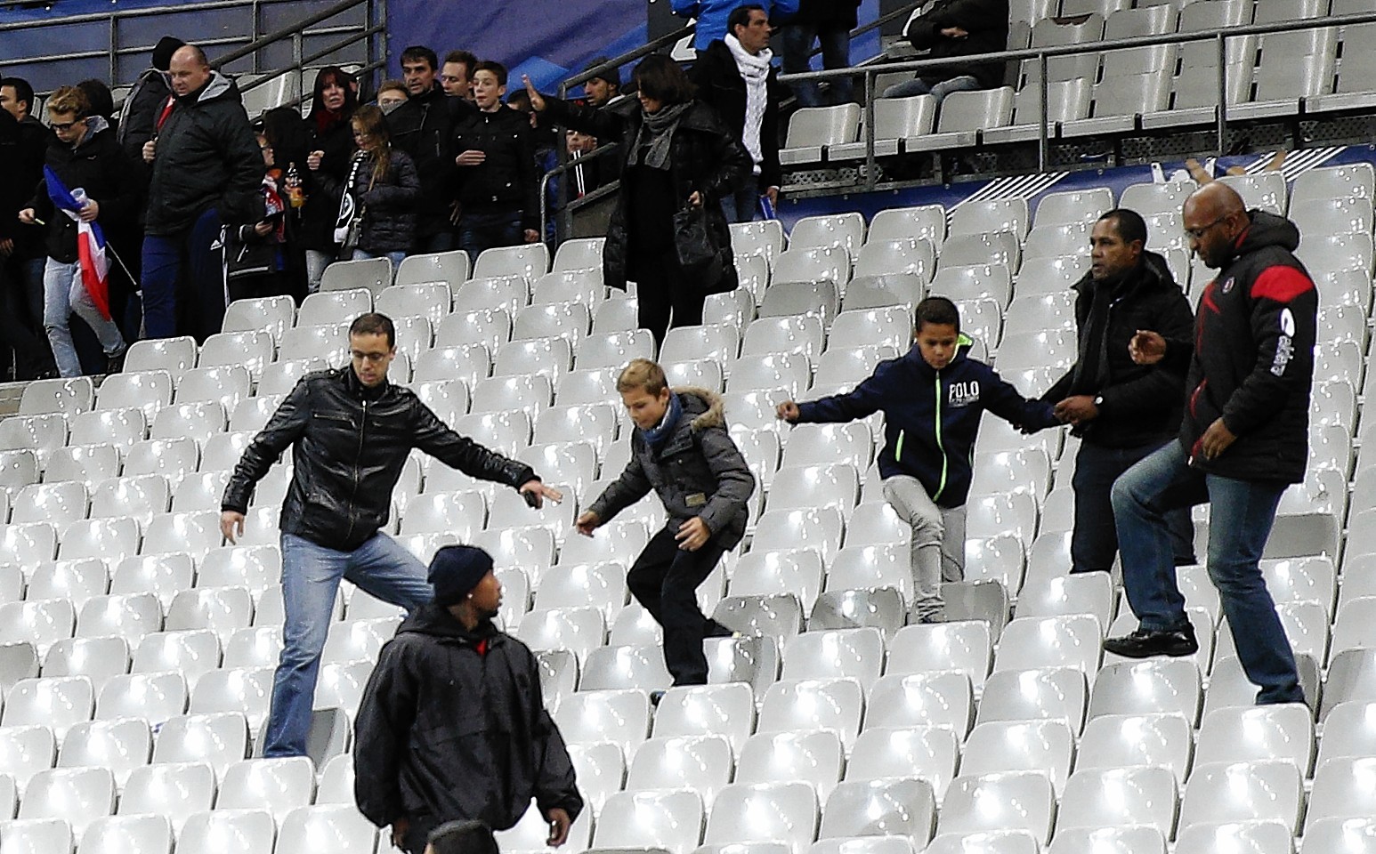 Soccer fans leave the Stade de France stadium after an international friendly soccer match in Saint Denis, outside Paris, Friday, Nov. 13, 2015. An explosion occurred outside the stadium. Several dozen people were killed in a series of unprecedented attacks around Paris on Friday, French President Francois Hollande said, announcing that he was closing the country's borders and declaring a state of emergency. 