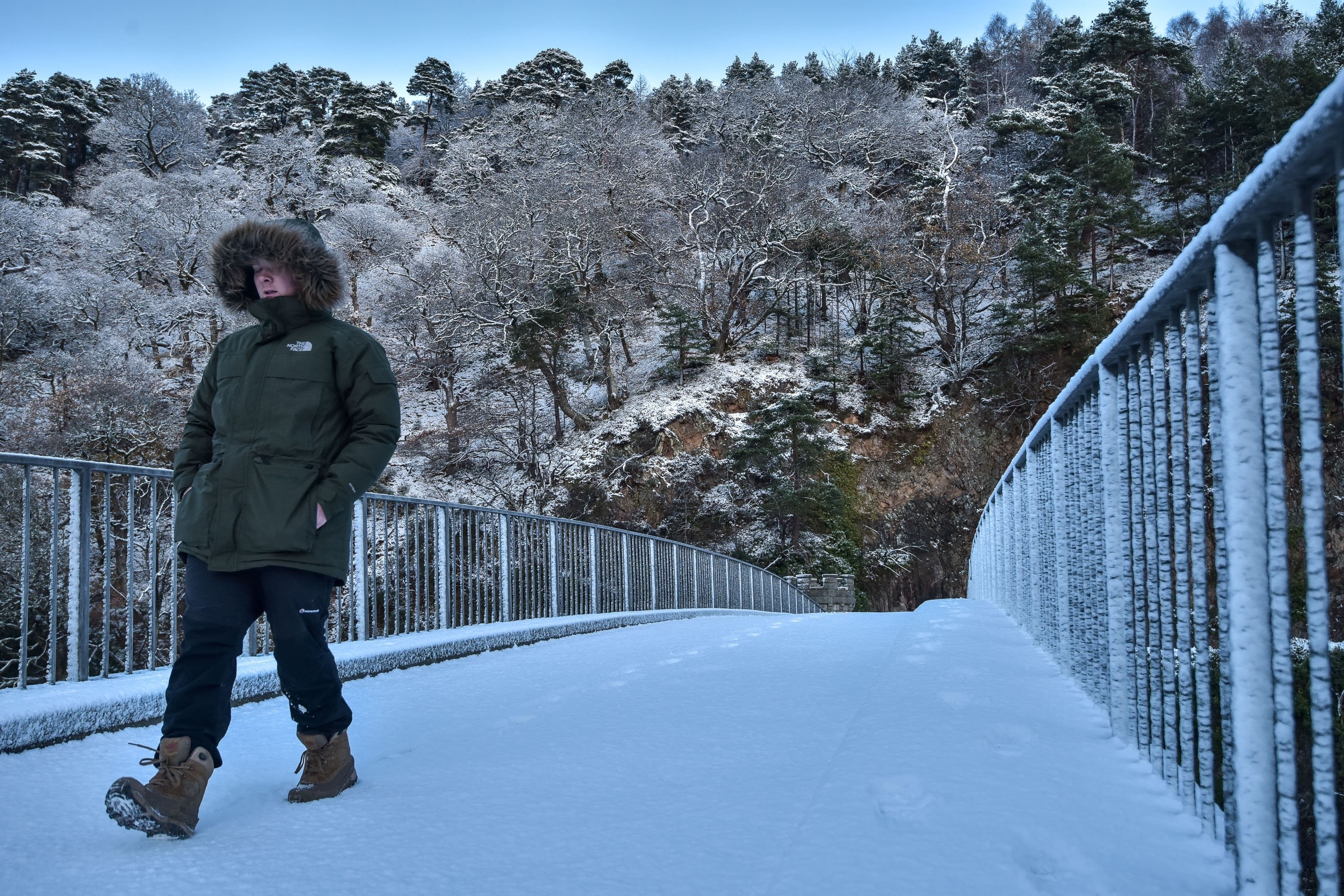 A man walks through snow on the Craigellachie Bridge in Craigellachie, Moray on November 30 2015. Storm Clodagh has brought high winds and snow showers which covered the north of Scotland.