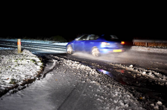 A car carefully maneuvers a snowy turn on the A96