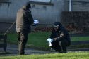 A Police officer is seen with a metal object in an evidence bag on Foresterhill Road