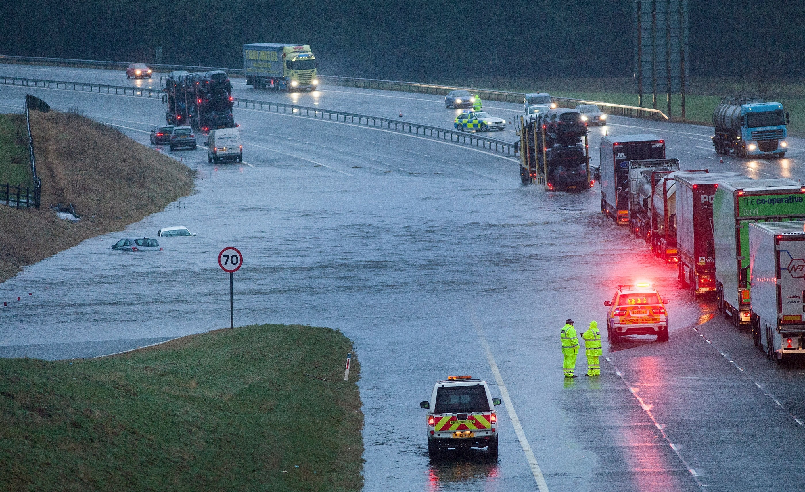 M74 northbound at J13 Abington is closed due to flooding caused by Storm Frank. Vehicles are seen floating in water and lorries pass with care. Dec 30 2015