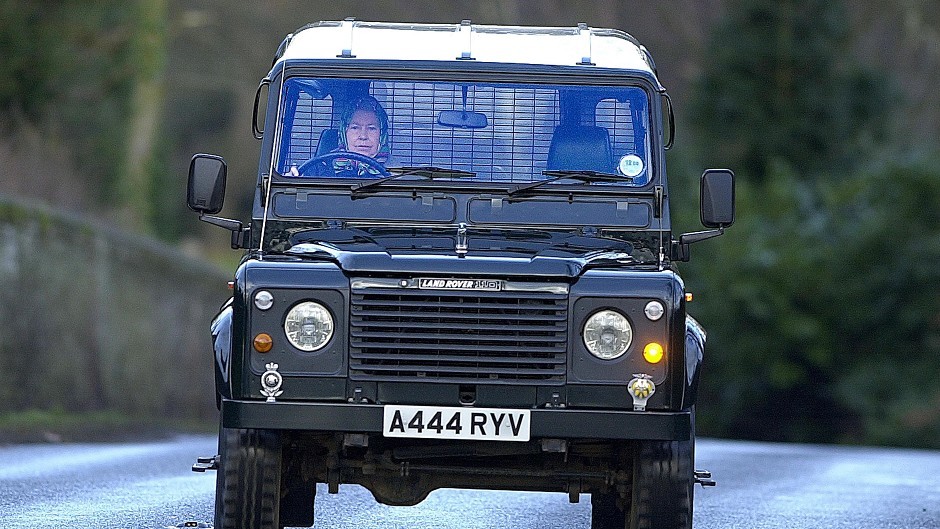 The Queen driving herself in a Land Rover Defender.