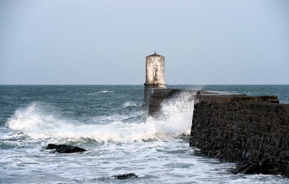 Waves crash against the harbour wall at Rosehearty