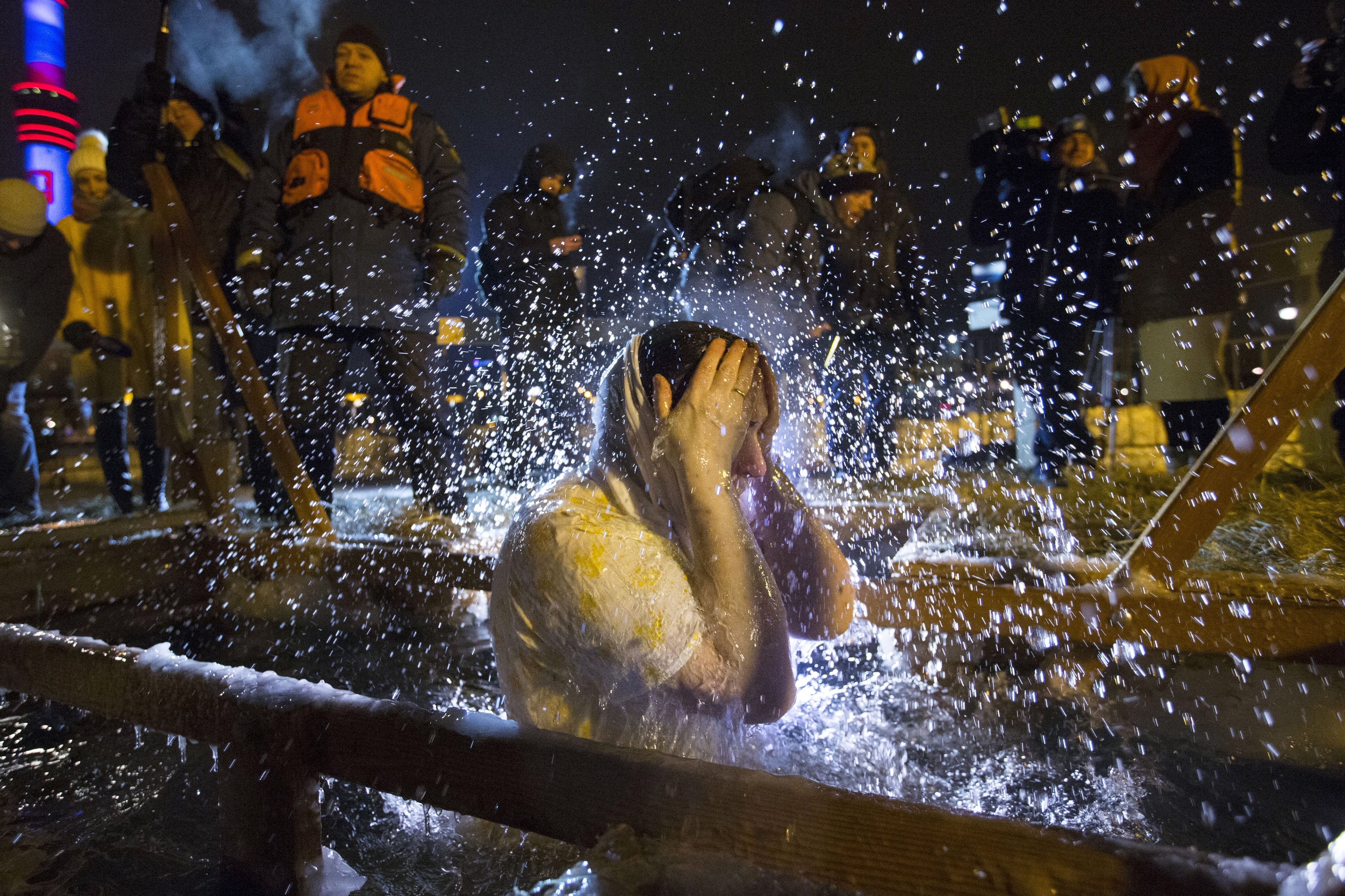 A Russian Orthodox believer bathes in the icy water on Epiphany at the Church of the Holy Trinity in Ostankino near TV Tower in Moscow, Russia, Monday, Jan. 18, 2016. Water that is blessed by a cleric on Epiphany is considered holy and pure until next year's celebration, and is believed to have special powers of protection and healing. The Russian Orthodox Church follows the old Julian calendar, according to which Epiphany falls on Jan. 19. (AP Photo/Alexander Zemlianichenko Jr)