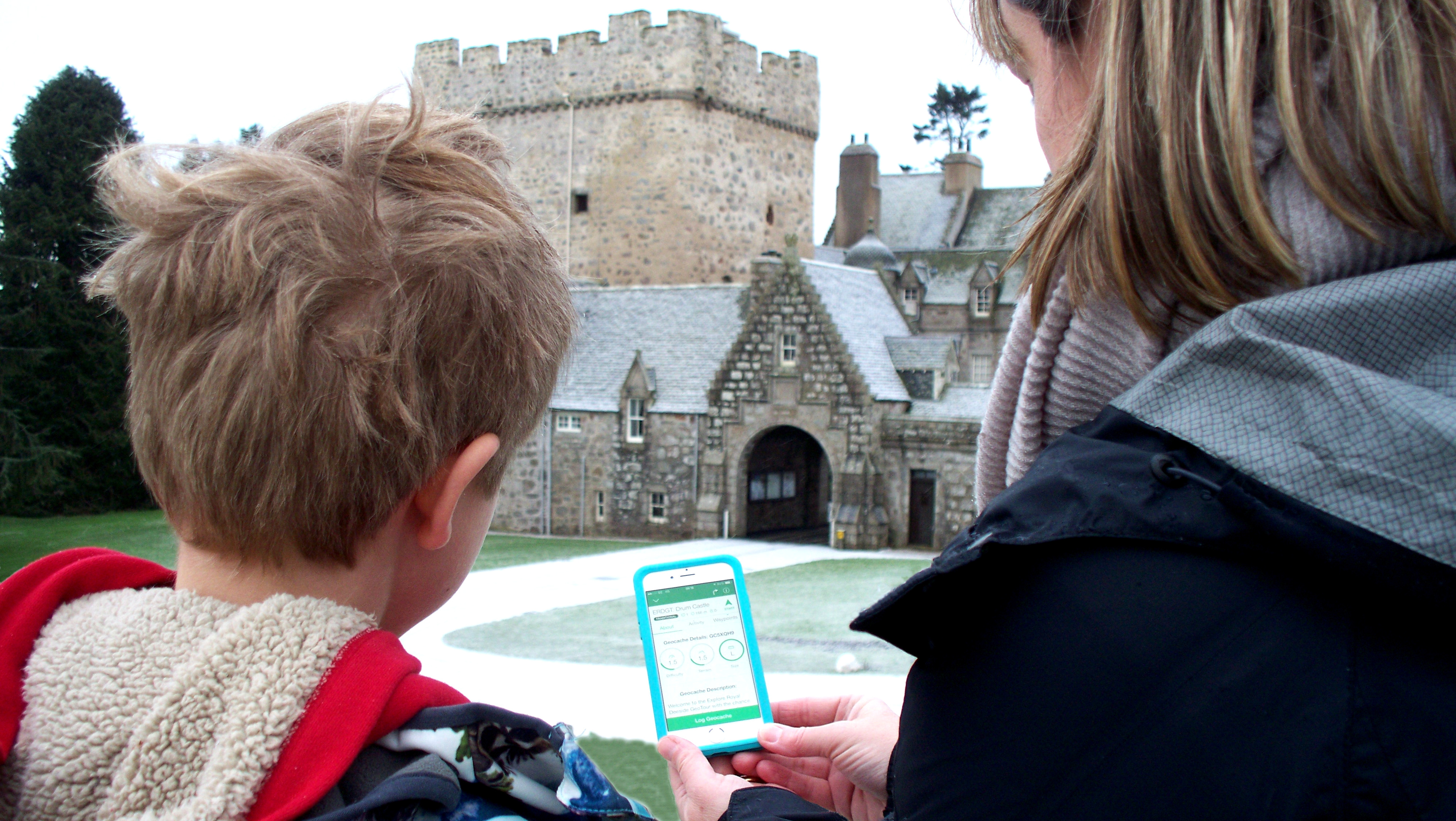 A family at Drum Castle tracking down a cache on the Explore Royal Deeside GeoTour