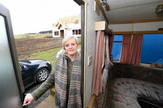 Emily Macdonald of Woodside, West Park, Strathpeffer with their partially built home and the caravan