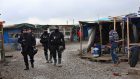 French police officers patrol in the migrant camp in Calais (AP)