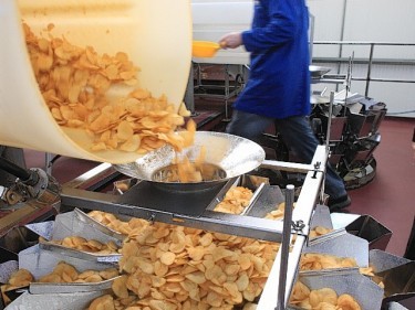 Crisps being flavoured with seasoning.