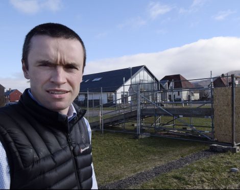 Councillor Ben Thompson by the full-scale mock-up of the original proposed flood defences in Caol