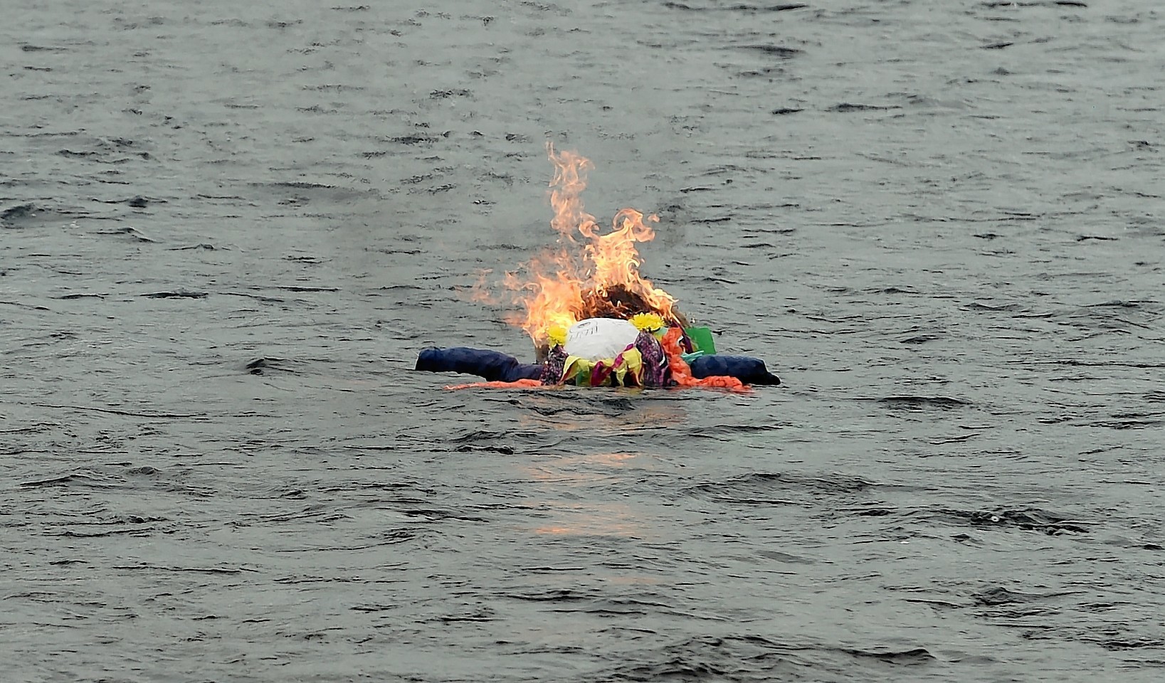 The burning doll floats down the river