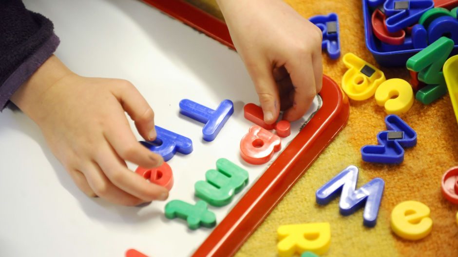 A child arranging alphabet magnets on a white board