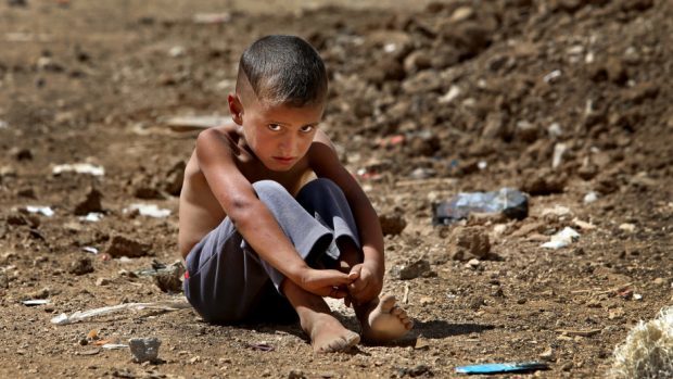 A Syrian refugee boy sits on the ground at a temporary refugee camp in the eastern Lebanese town of Al-Faour (AP)