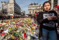 People stop and look at floral tributes at a memorial site at the Place de la Bourse in Brussels