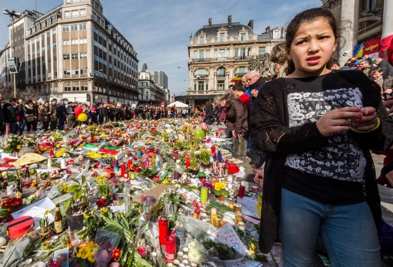 People stop and look at floral tributes at a memorial site at the Place de la Bourse in Brussels
