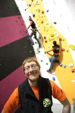 Oliver Millington surrounded by the colourful climbing walls of Three Wise Monkeys Climbing, which opens in May