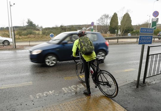 A cyclist crosses the A9 at Tore Roundabout
