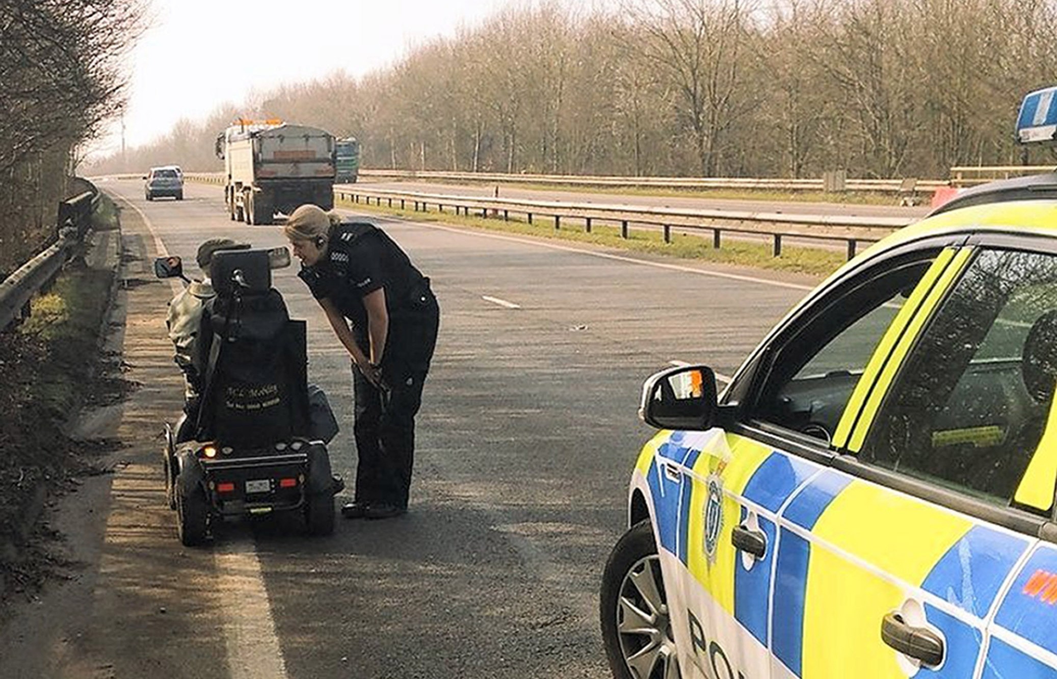 Police Officer Katie Breeds speaking to a  'very confused' 92-year-old man who found himself on his mobility scooter on the busy A2011 near Crawley, West Sussex after taking a wrong turn.