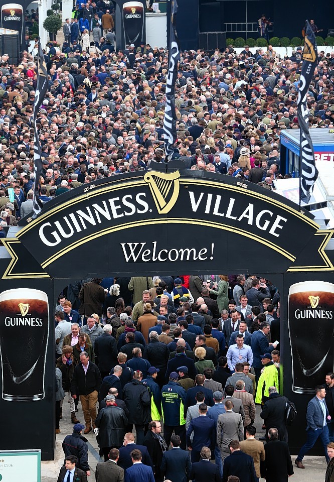 Racegoers walk through the Guinness Village before the start of day one at Cheltenham