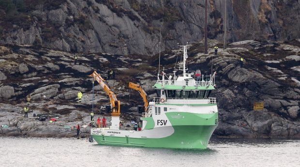 A recovery vessel lifts parts of the crashed helicopter